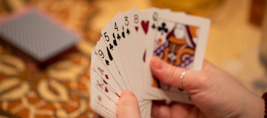 A selective focus of a hand of playing cards held by a person with a blurry background
